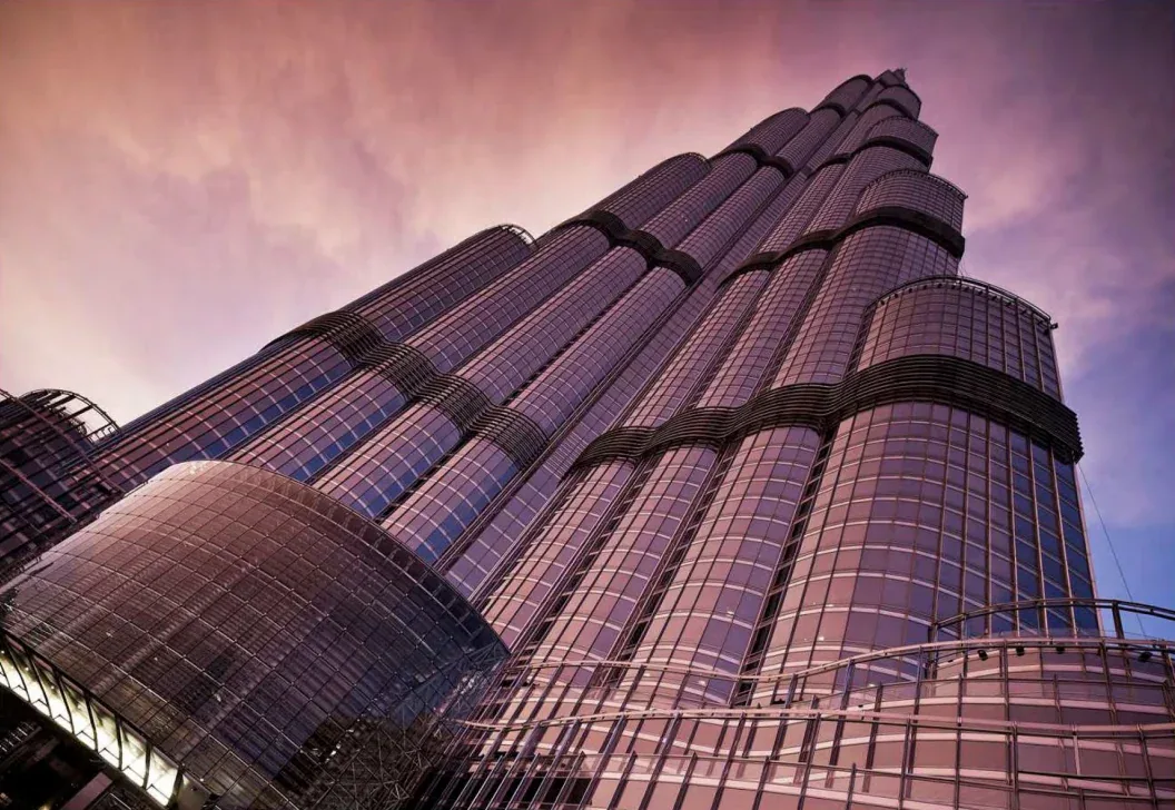 Looking up at the Burj Khalifa glass facade against a pink evening sky