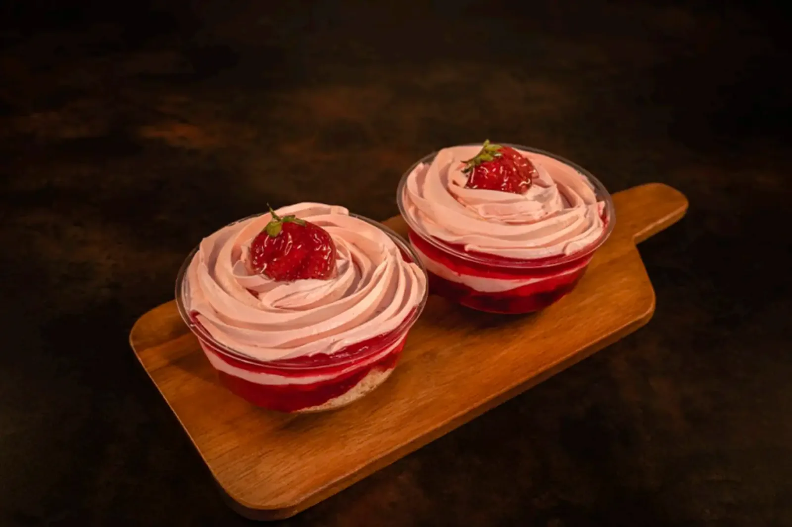 Pink frosted cupcakes on a wooden serving board